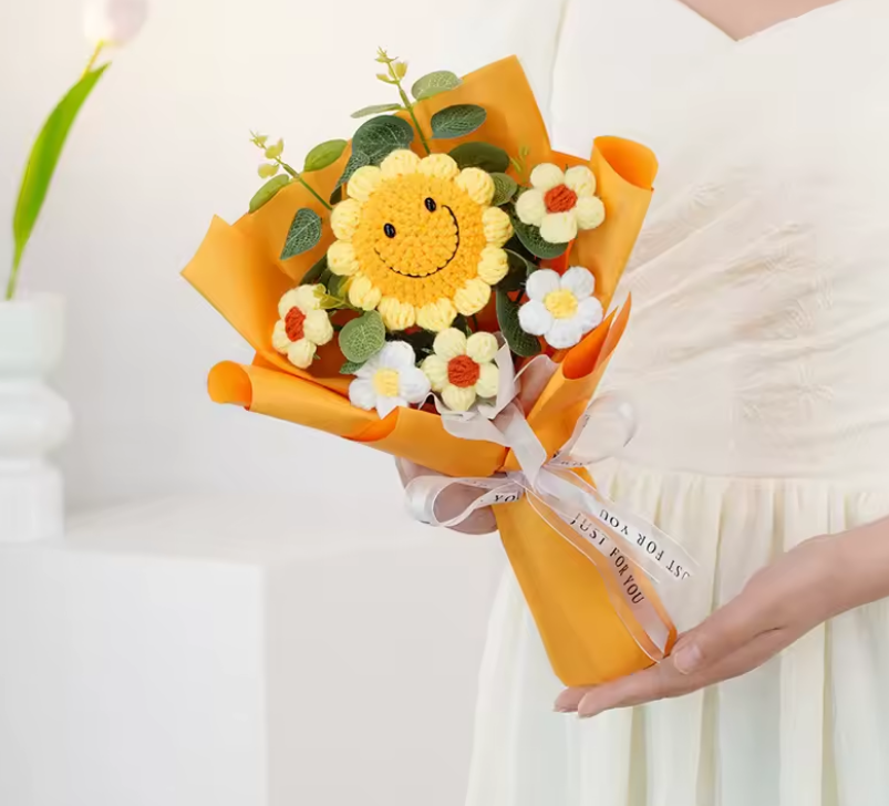 Bouquet with a sunflower-shaped center held by a person wearing a white dress.