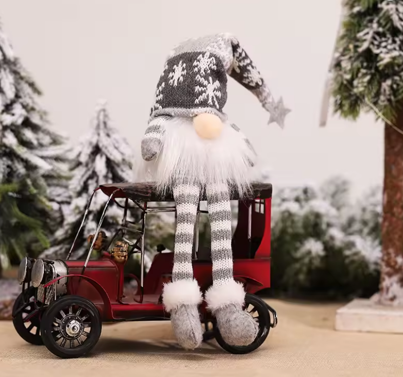 Gnome with a long scarf sitting on a red toy car in a snowy landscape