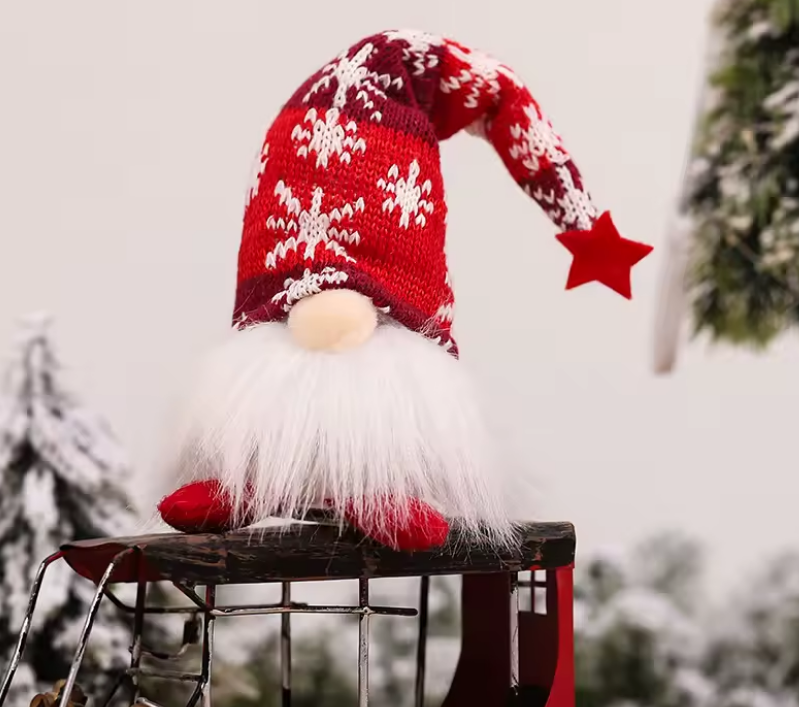 Christmas-themed gnome with red hat and white beard on a stool outdoors.