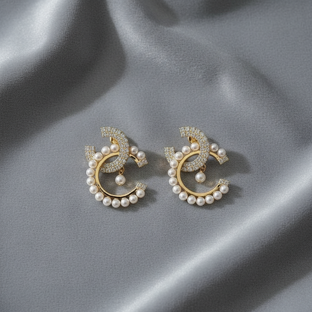 Pair of gold and pearl earrings on a gray fabric background