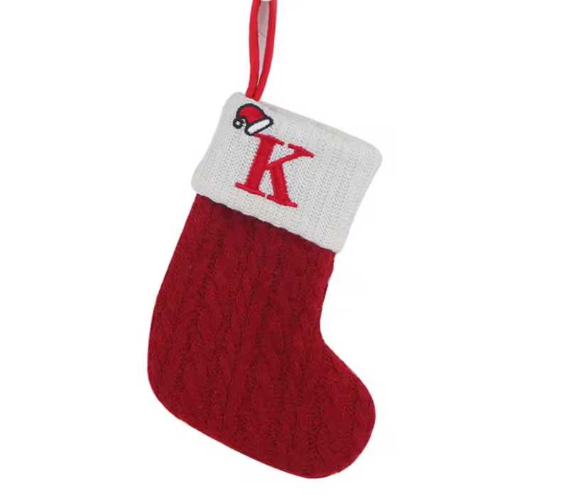 Red knitted Christmas stocking with a white cuff featuring a red 'K' on a white background.