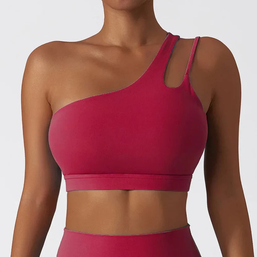 Person wearing a pink one-shoulder top against a plain background