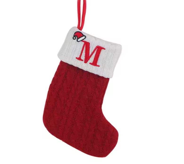 Red knitted Christmas stocking with a white cuff featuring a red letter 'M' and a small Santa face, on a white background.