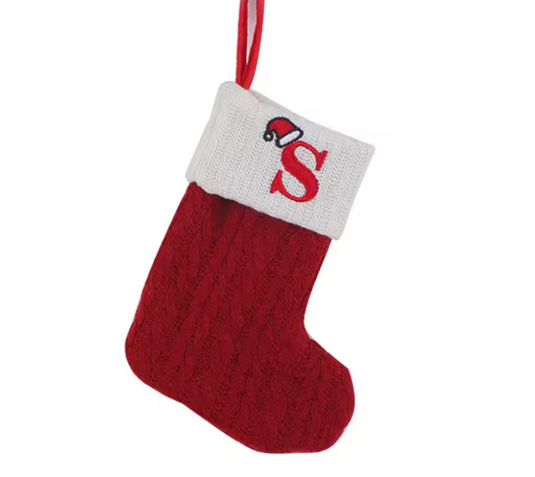 Red knitted Christmas stocking with a white cuff featuring a red letter 'S' on a white background.