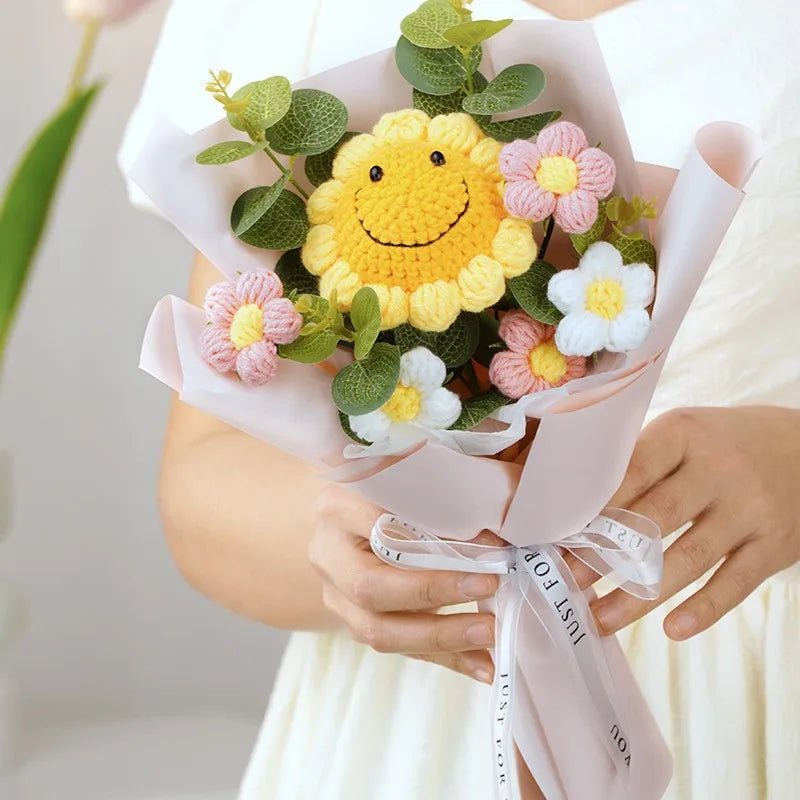 Bouquet of knitted flowers with a smiley face center held by a person.