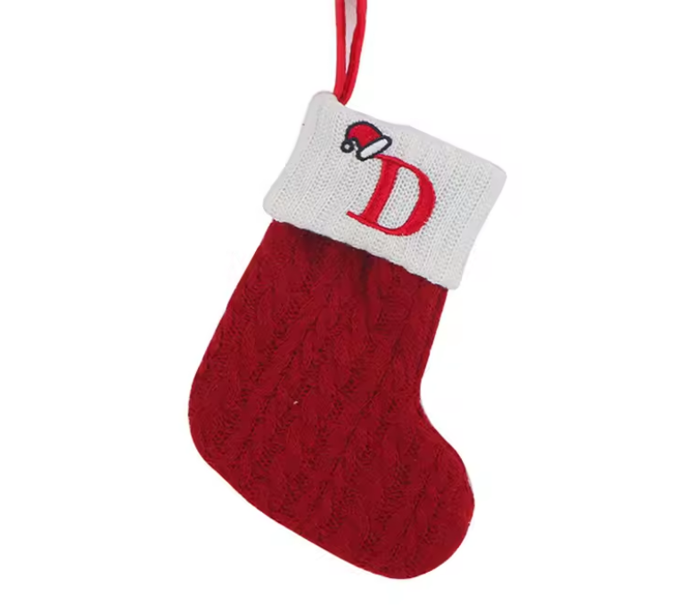Red knitted Christmas stocking with white cuff featuring a red 'D' and Santa hat on a white background.