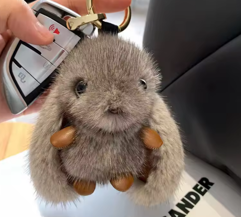 Plush keychain shaped like a rabbit held by a person with a car key.