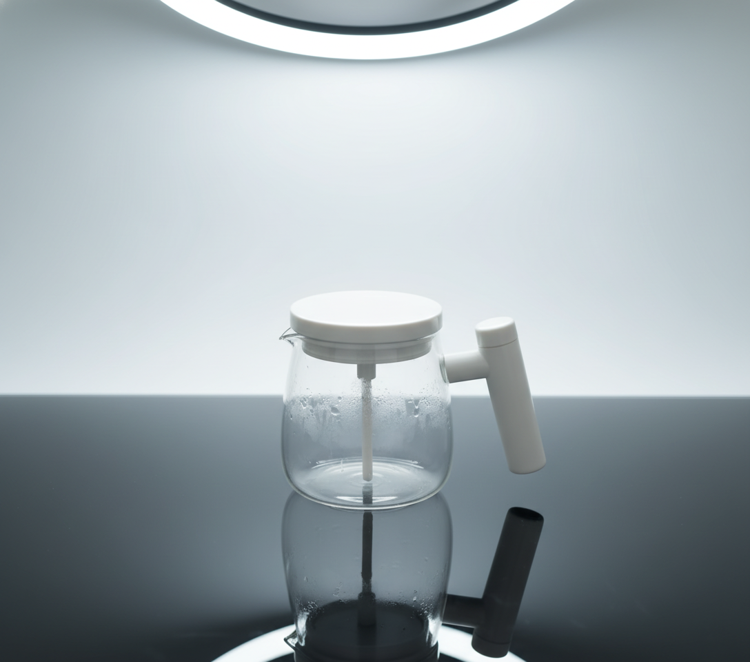 Clear glass coffee maker with white lid and handle on a light gray background