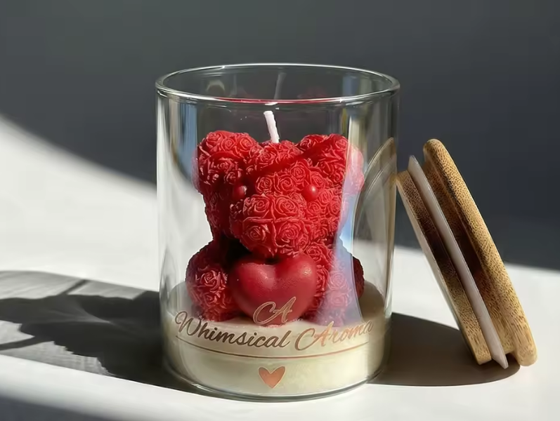 Glass candle holder with red heart and bear-shaped candles on a white surface.