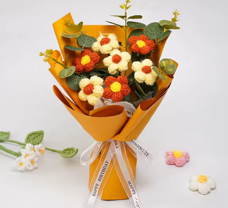 Bouquet of knitted flowers in orange paper wrapping with a white ribbon on a light background