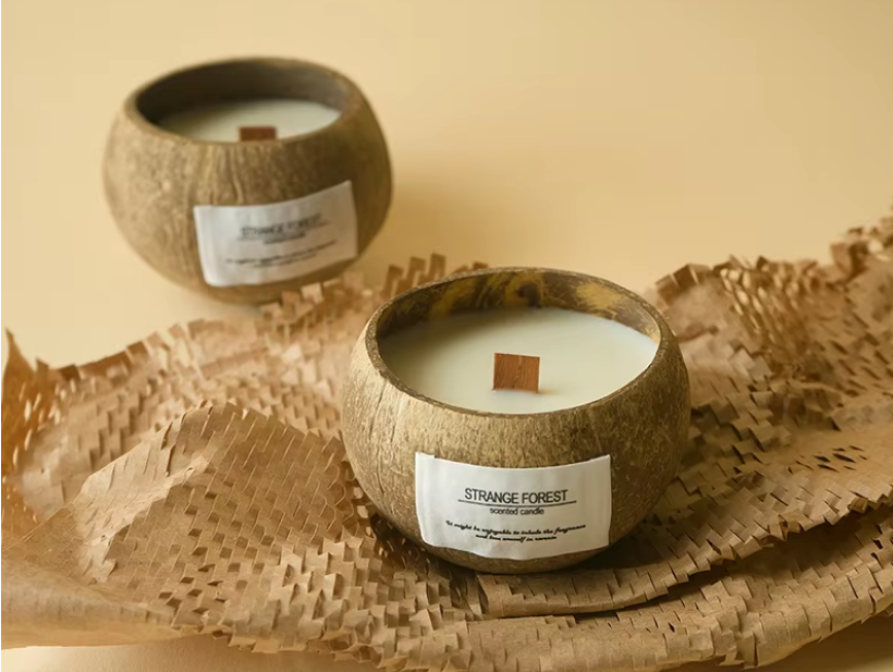 Two coconut shell candles labeled 'Strange Forest' on a woven mat.