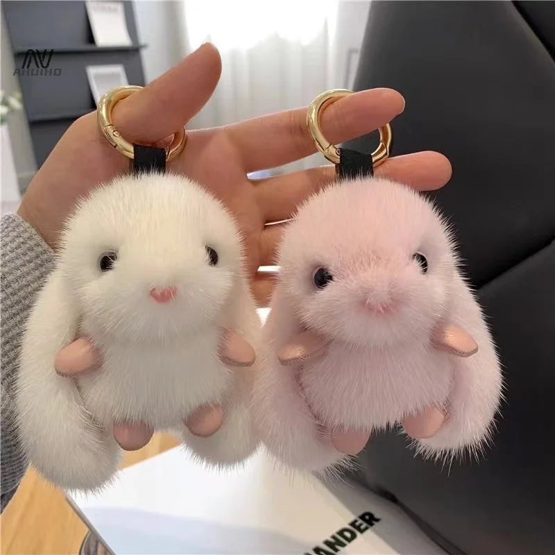 Two fluffy bunny-shaped keychains held by a hand.