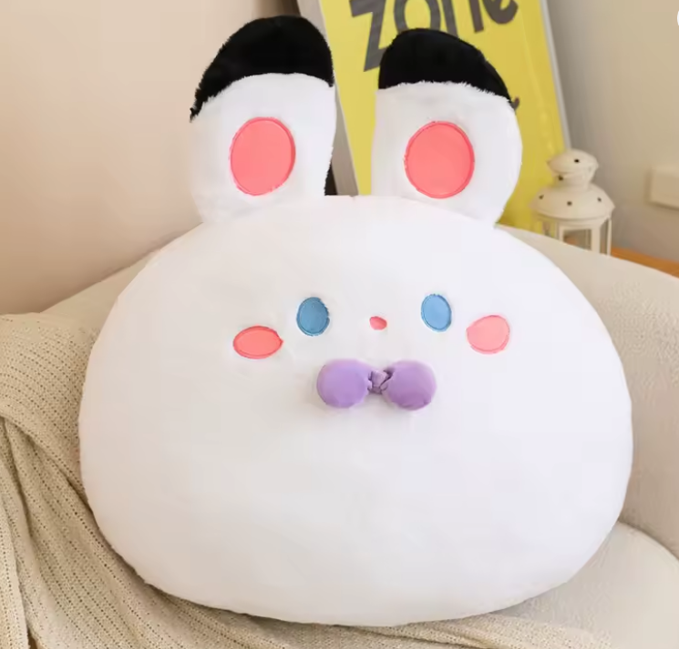 White plush toy with colorful face on a beige surface