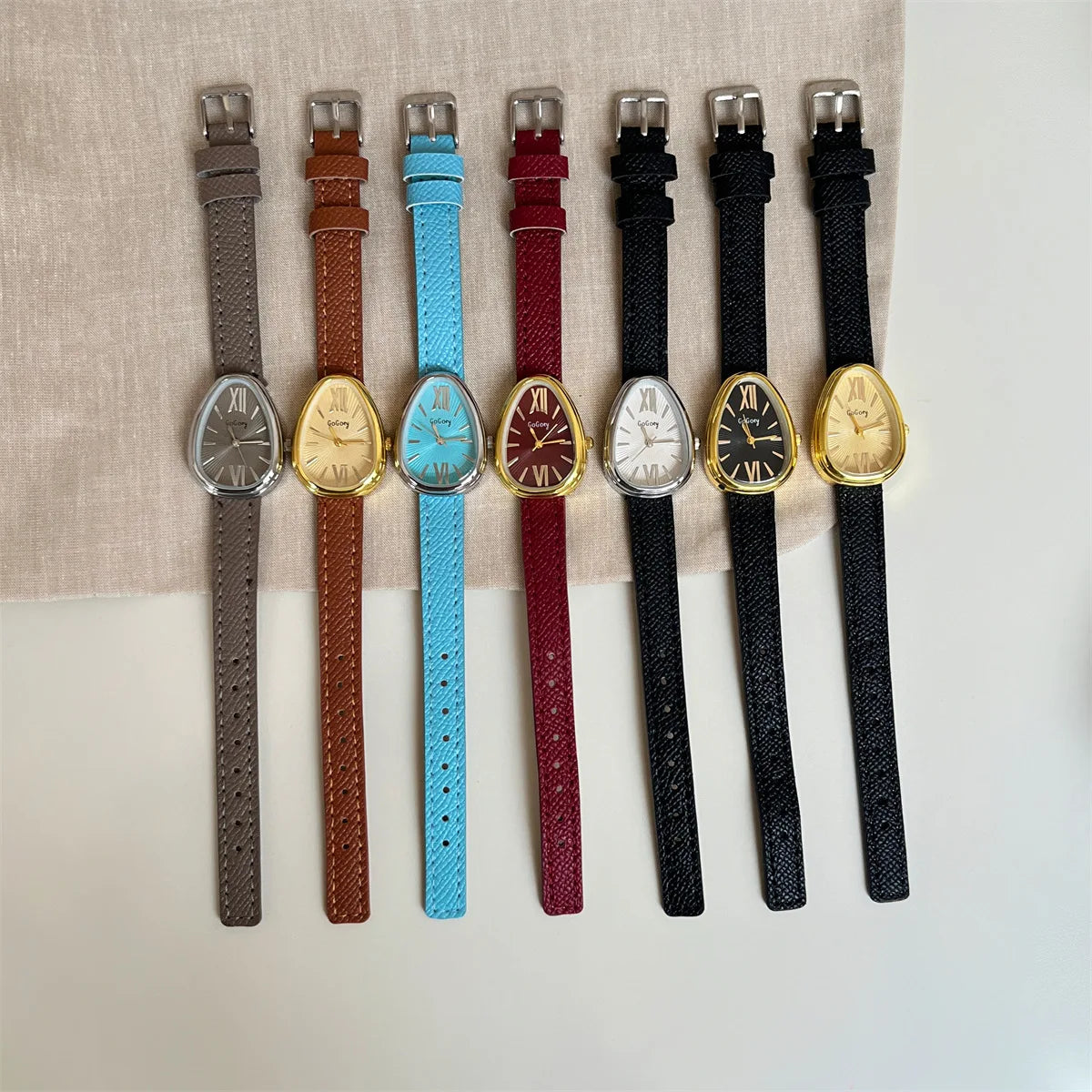 Set of watches with different colored straps on a neutral background