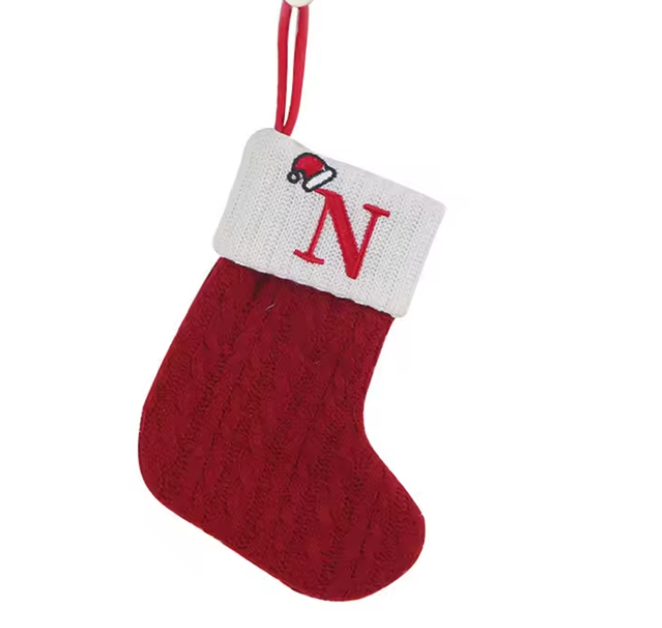 Red Christmas stocking with white cuff featuring a letter 'N' on a white background