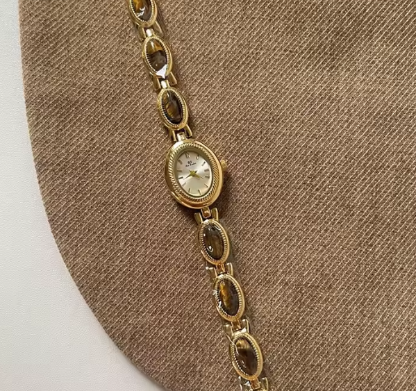 Gold wristwatch on a brown textured surface