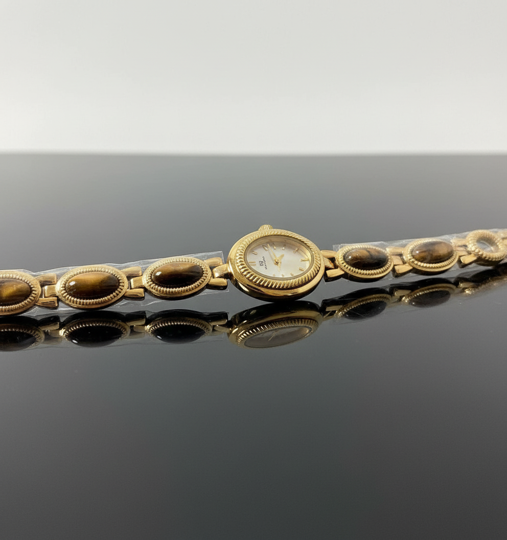 Gold bracelet with embedded stones on a reflective surface