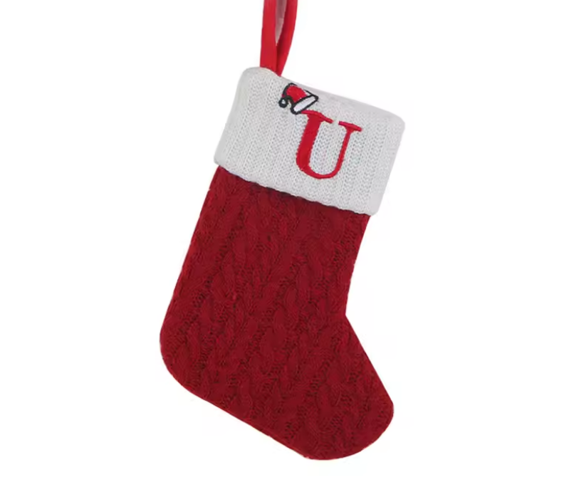 Red knitted Christmas stocking with white cuff and letter 'U' on a white background