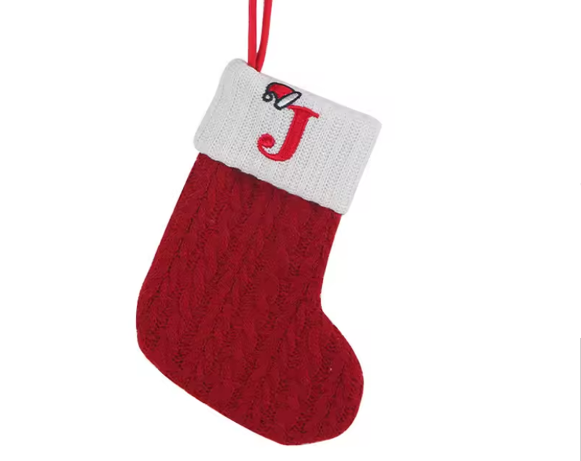 Red knitted Christmas stocking with a white cuff and letter 'J' on a white background